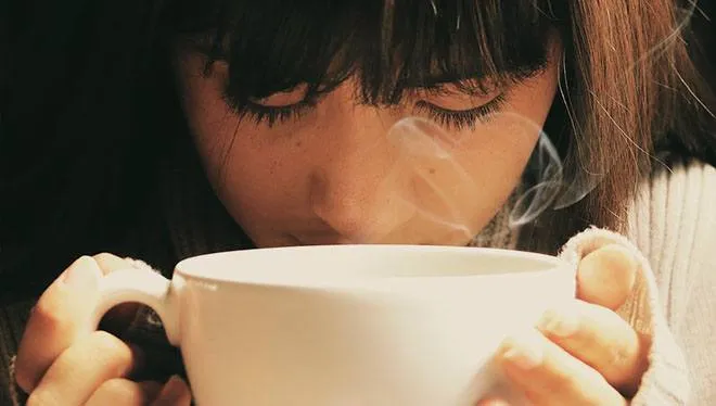 девушка вдыхает аромат кофе