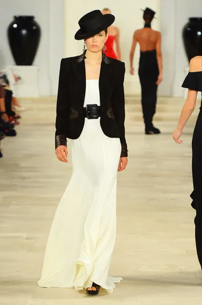 Модель в длинном белом платье и черном пиджаке