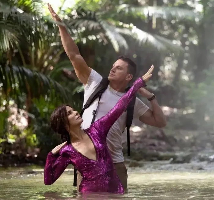Актер Ченнинг Татум и Сандра булок стоят в воде подняв руки.