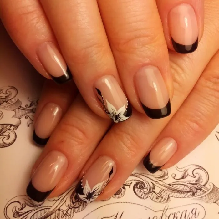 Небольшой цветок на черно-белых ногтях делает образ женщины романтическим.