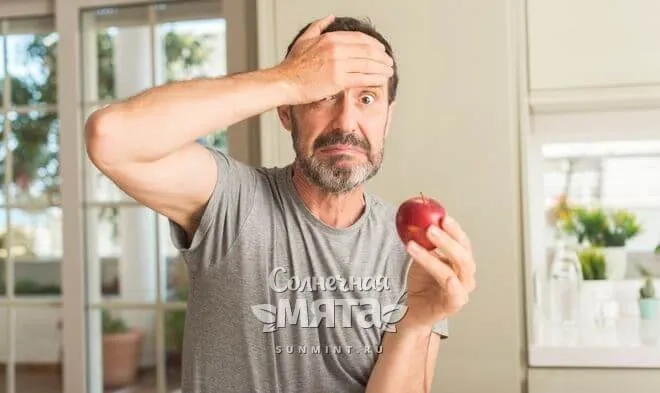 Взрослый мужчина удивляется новой диете, держа в руках яблоко, фото