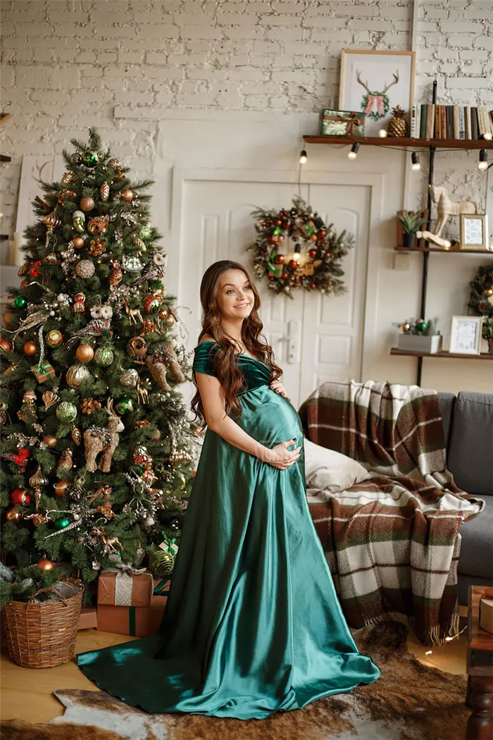 Фотосессия беременной в зеленом платье на фоне новогодней елки
